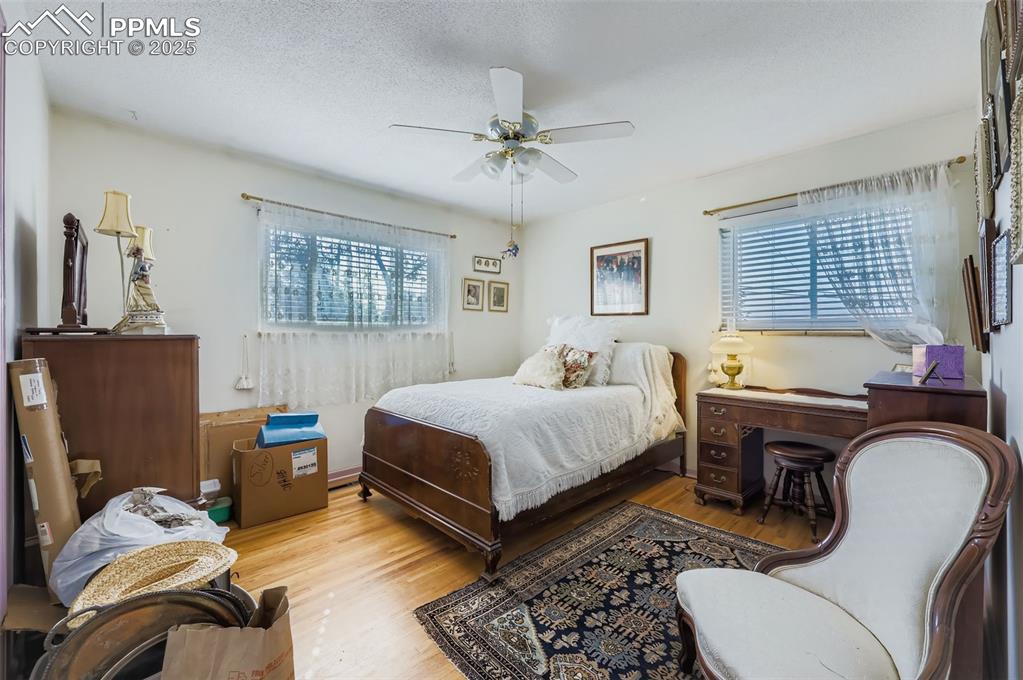 Image 14 of 23: Bedroom featuring wood finished floors, a ceiling fan, and a textured ceili