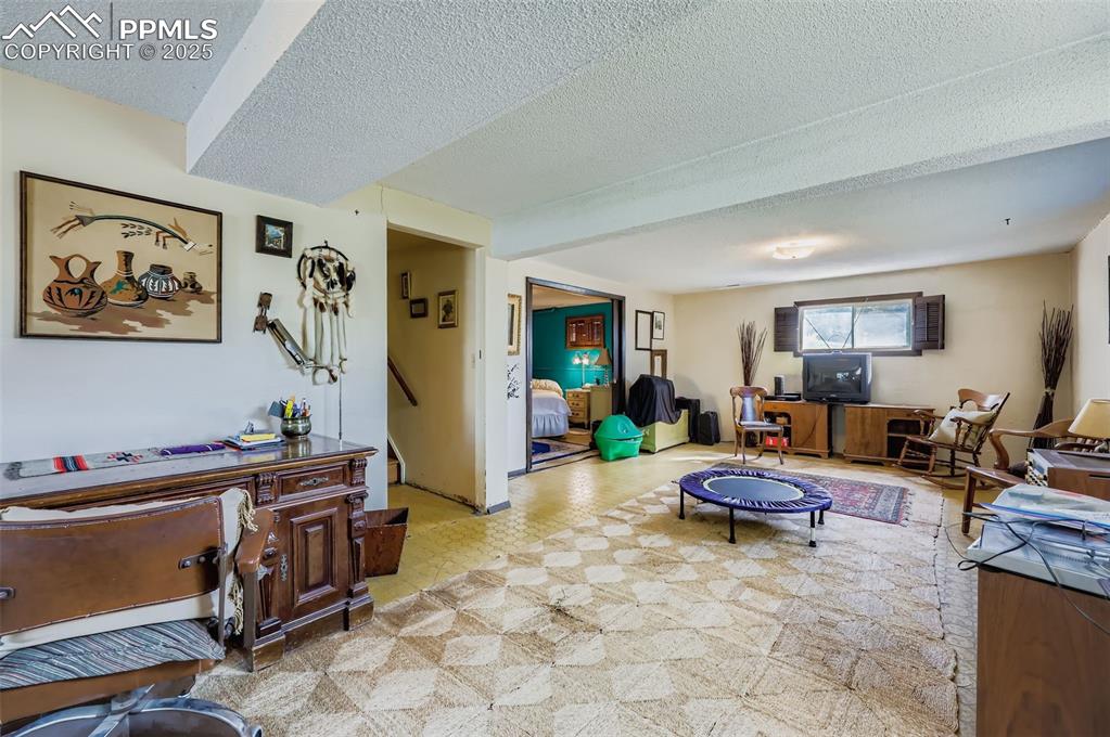 Image 17 of 23: Living room with a textured ceiling and light floors