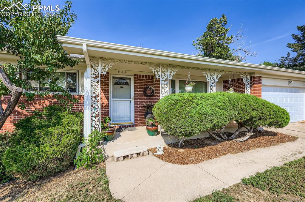 Image 2 of 23: View of front of house with a garage, brick siding, a porch, and driveway