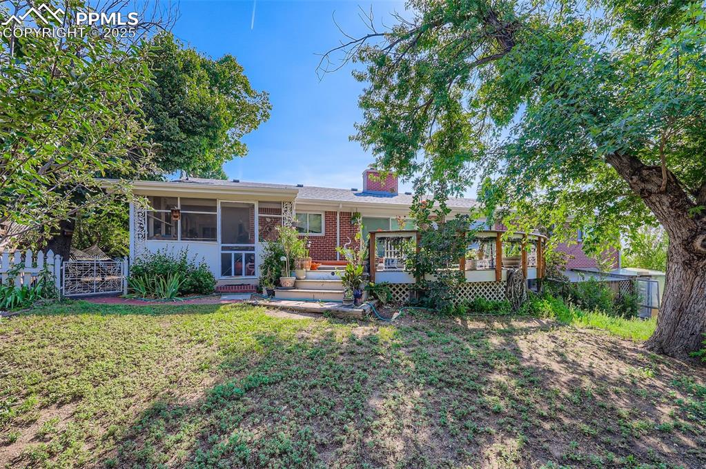 Image 22 of 23: View of front of property featuring a sunroom, a deck, a chimney, and brick