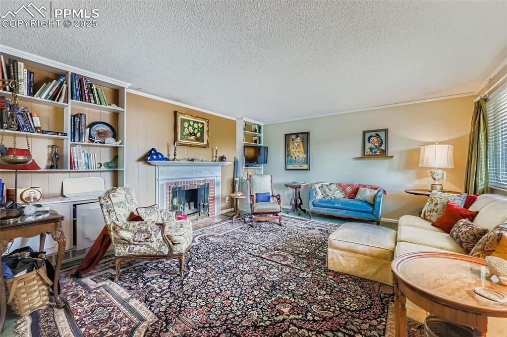 Image 3 of 23: Living room with built in shelves, a fireplace, a textured ceiling, and orn