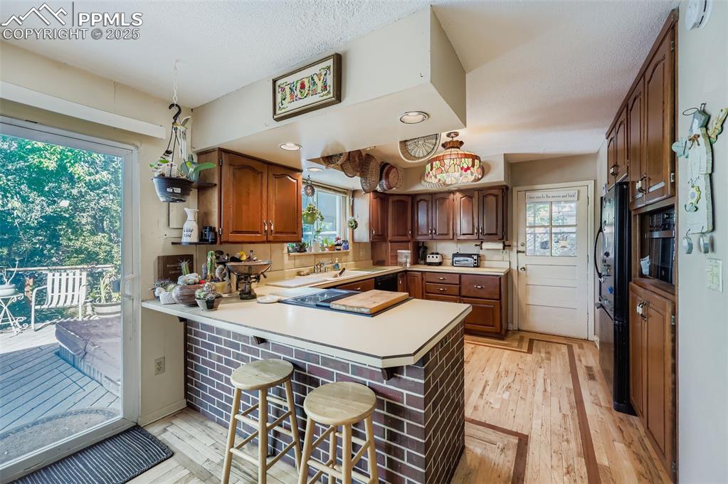 Image 5 of 23: Kitchen with a peninsula, light countertops, light wood-style flooring, a k