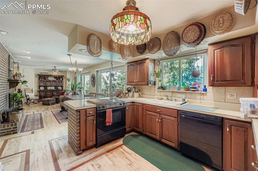 Image 6 of 23: Kitchen with black appliances, light countertops, light wood finished floor
