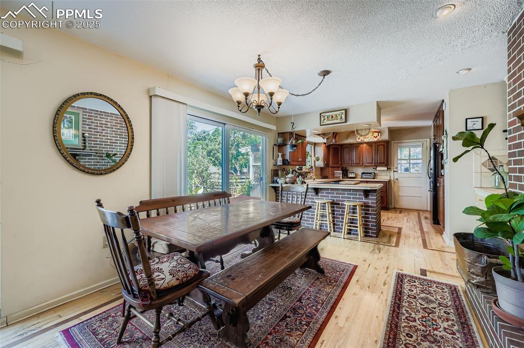 Image 9 of 23: Dining space featuring light wood finished floors, a chandelier, and a text