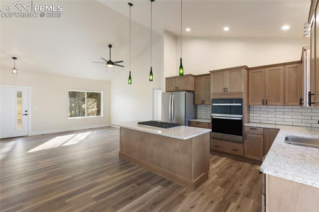 Image 13 of 38: Kitchen with high vaulted ceiling, open floor plan, tasteful backsplash, a