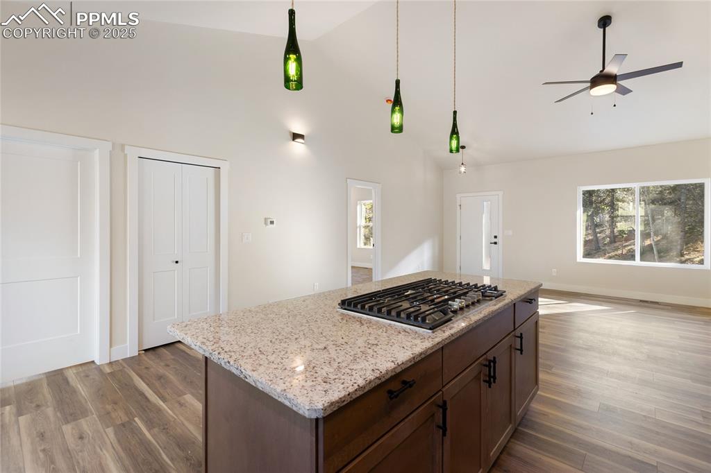 Image 15 of 38: Kitchen with dark wood finished floors, ceiling fan, light stone countertop