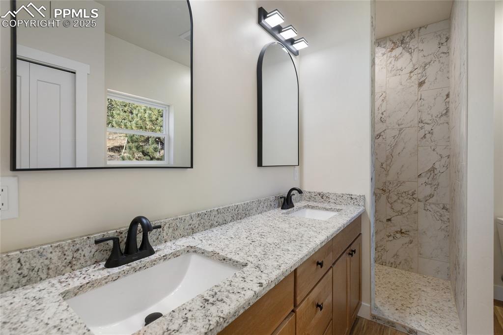 Image 21 of 38: Bathroom with double vanity and a tile shower