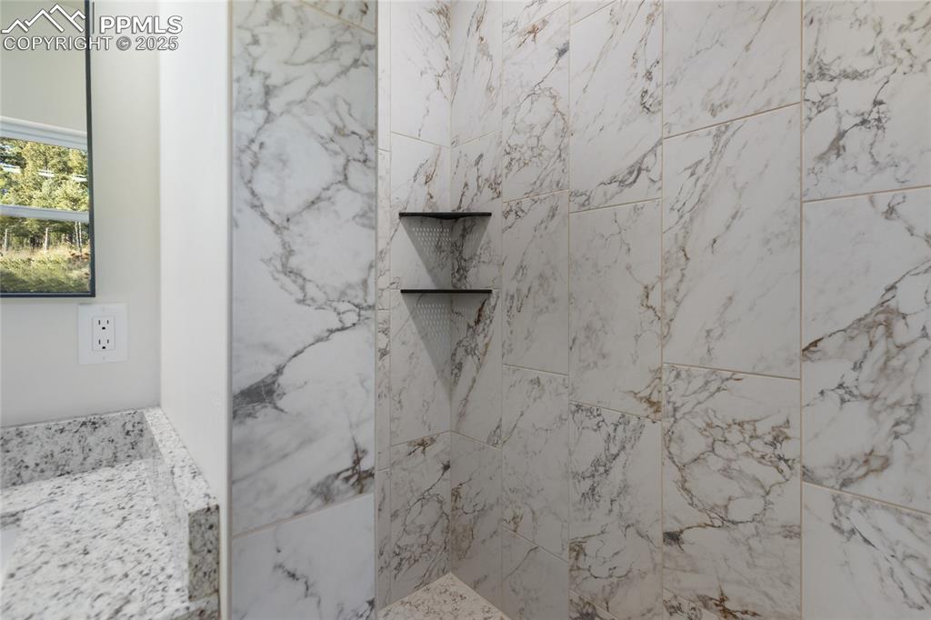 Image 23 of 38: Full bathroom with a marble finish shower and vanity