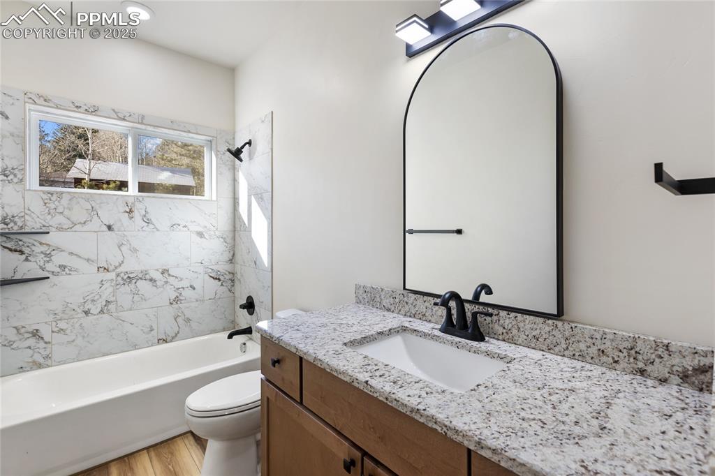 Image 30 of 38: Full bath with shower / bath combination, vanity, and light wood-style floo