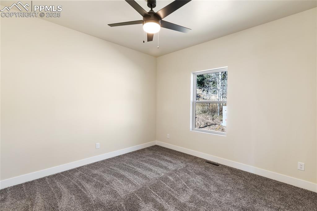 Image 31 of 38: Empty room featuring dark carpet and a ceiling fan