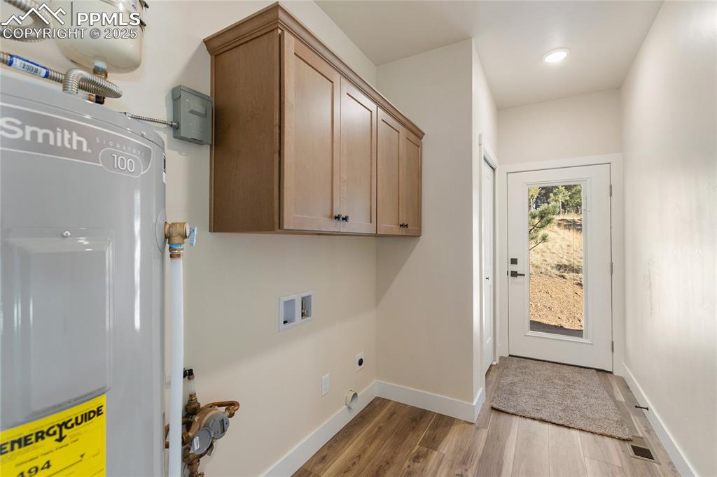 Image 34 of 38: Laundry room featuring electric water heater, cabinet space, light wood-typ