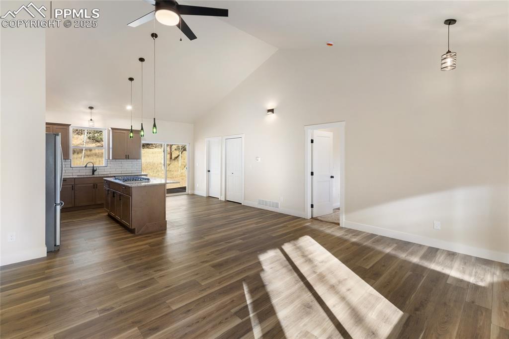 Image 7 of 38: Unfurnished living room featuring high vaulted ceiling, dark wood-type floo