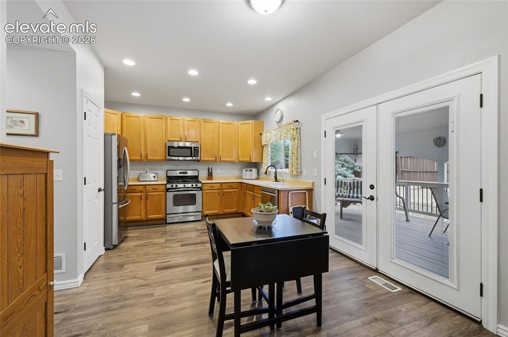 Image 11 of 41: Kitchen with wood-finish flooring, recessed lighting, and stainless steel a
