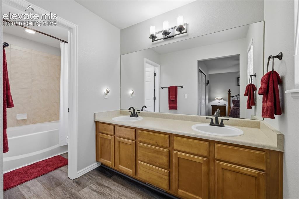 Image 16 of 41: Double vanity with wood-finish cabinetry, a large wall-mounted mirror, and 