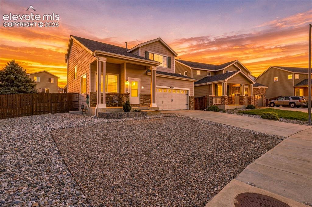 Image 2 of 41: Two-story residence featuring a covered front porch, attached garage, and s