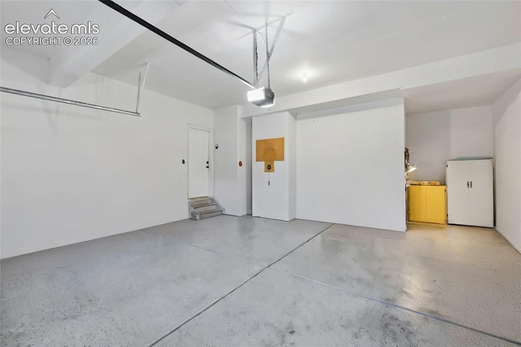 Image 22 of 41: Spacious, oversized garage featuring epoxied concrete flooring and white wa