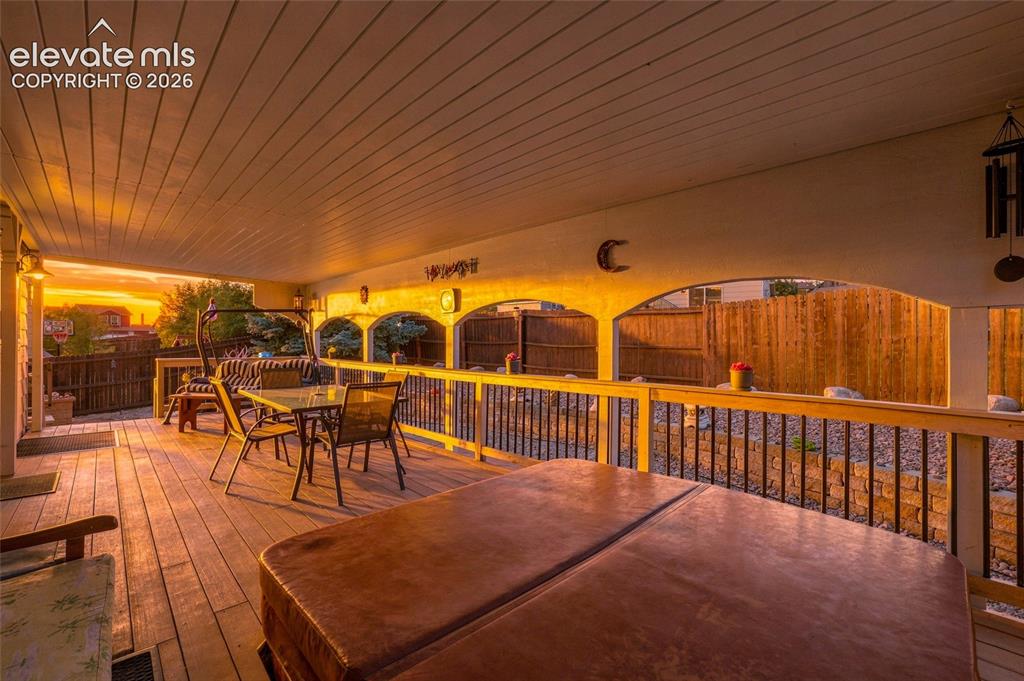 Image 24 of 41: Covered wood-finish deck featuring a hot tub and arched architectural detai