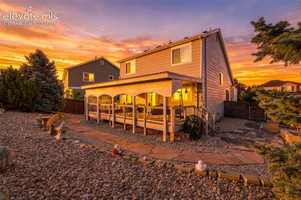 Image 26 of 41: Covered outdoor deck with white railing, leading to a stone patio