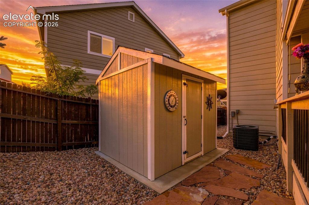 Image 29 of 41: Storage shed with a pitched roof, gravel landscaping, and a flagstone pathw