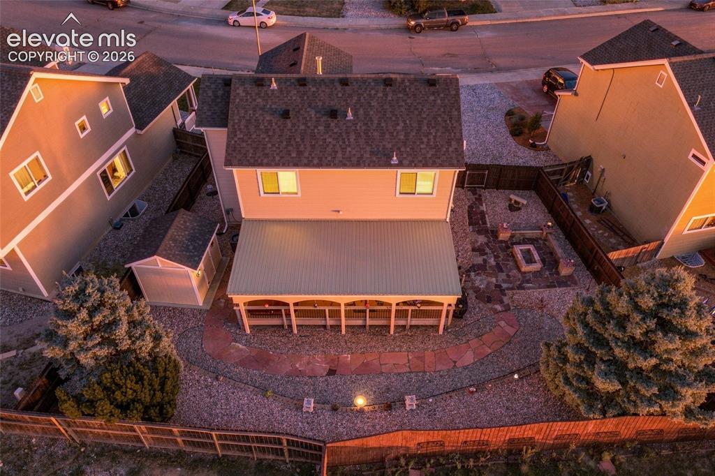 Image 30 of 41: Expansive backyard featuring a covered patio, stone fire pit area, and grav