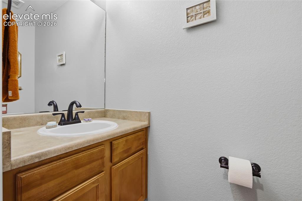 Image 8 of 41: Half-bath with wood-finish vanity with an integrated sink, a neutral counte