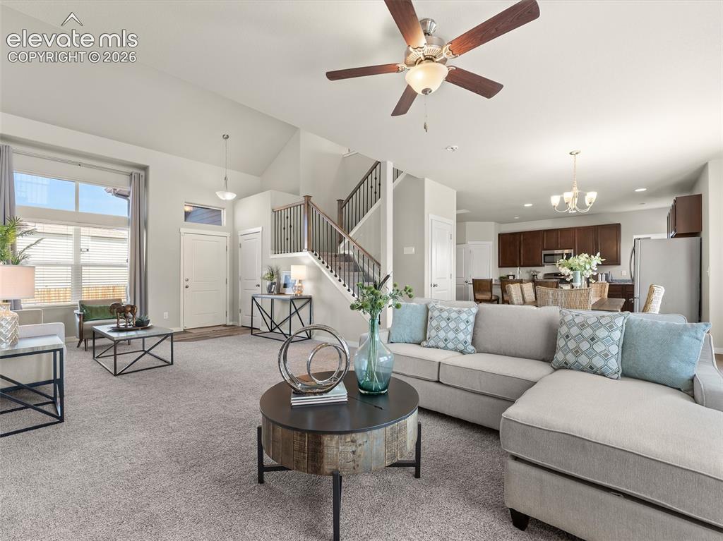 Image 10 of 46: Spacious living area featuring vaulted ceilings, a ceiling fan, and large w