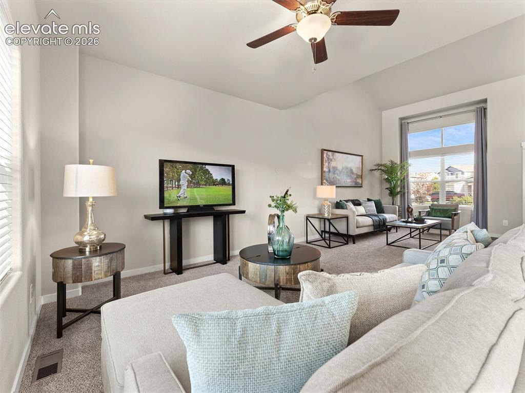 Image 11 of 46: Vaulted ceilings enhance this living space featuring neutral carpet floorin