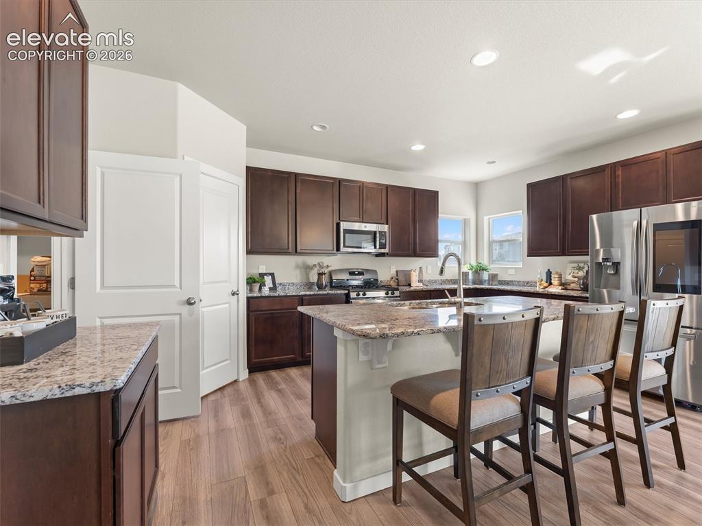 Image 15 of 46: Spacious kitchen featuring dark wood cabinetry, granite countertops, stainl
