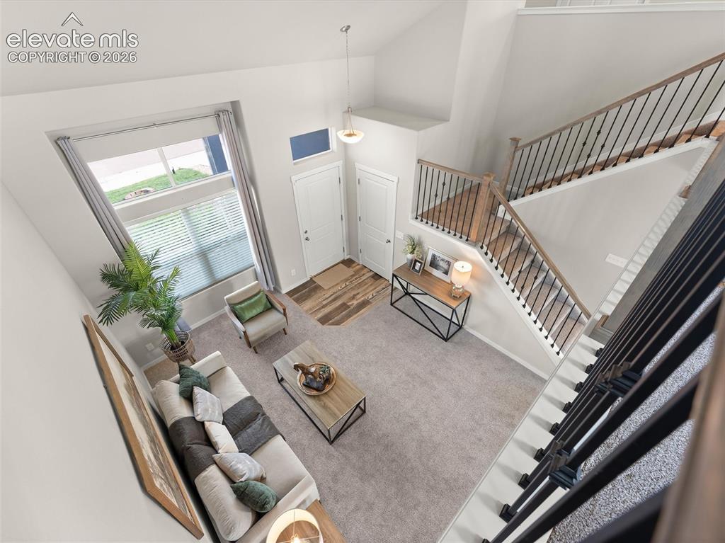 Image 24 of 46: Open-concept living space with a high ceiling, featuring a prominent stairc