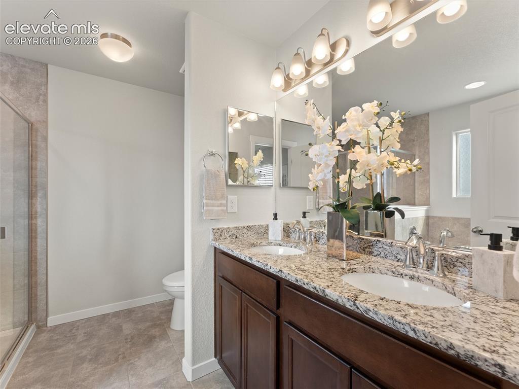Image 30 of 46: Double vanity featuring granite countertops, undermount sinks, and dark woo