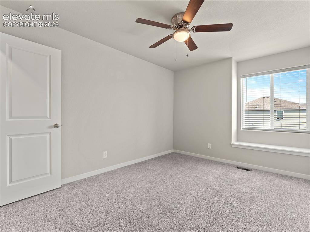 Image 32 of 46: Neutral-toned room featuring a large window with blinds and a built-in wind