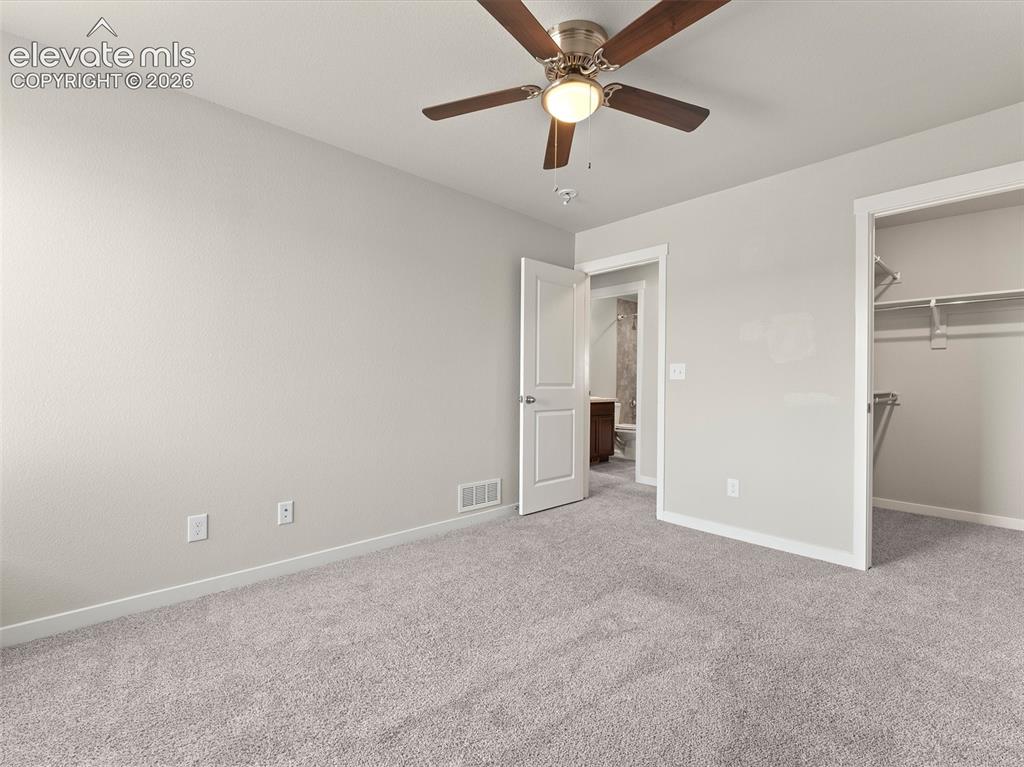 Image 33 of 46: Carpeted room featuring a ceiling fan with light fixture, light gray walls,