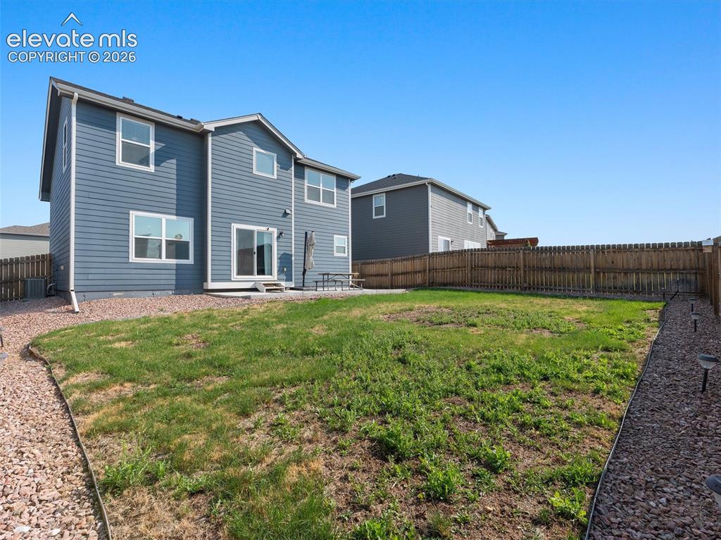 Image 37 of 46: Expansive backyard featuring a large grass area, wood privacy fencing, a co