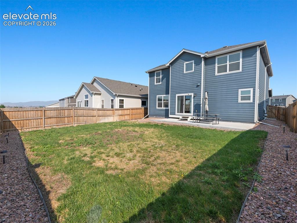 Image 38 of 46: Expansive backyard featuring a large grass area, wood privacy fencing, and 
