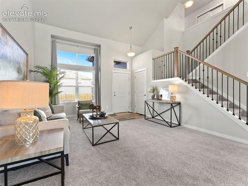Image 7 of 46: Vaulted ceiling living area with a large window featuring horizontal blinds
