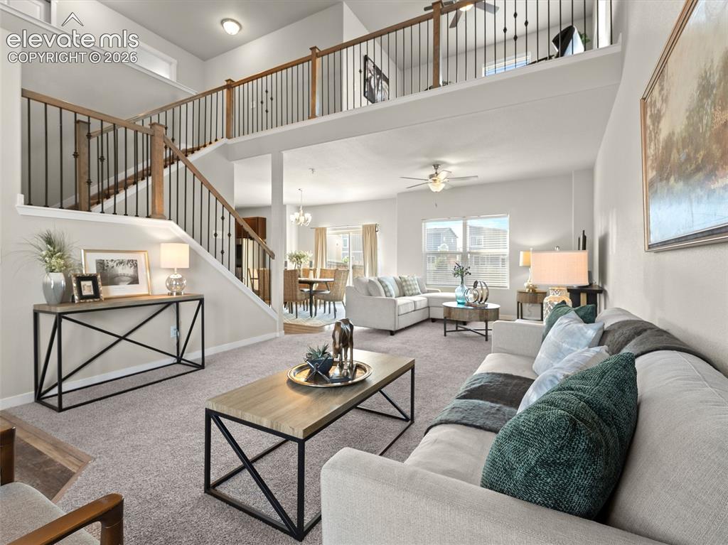 Image 8 of 46: Open-concept living area featuring a two-story ceiling, a staircase with wo