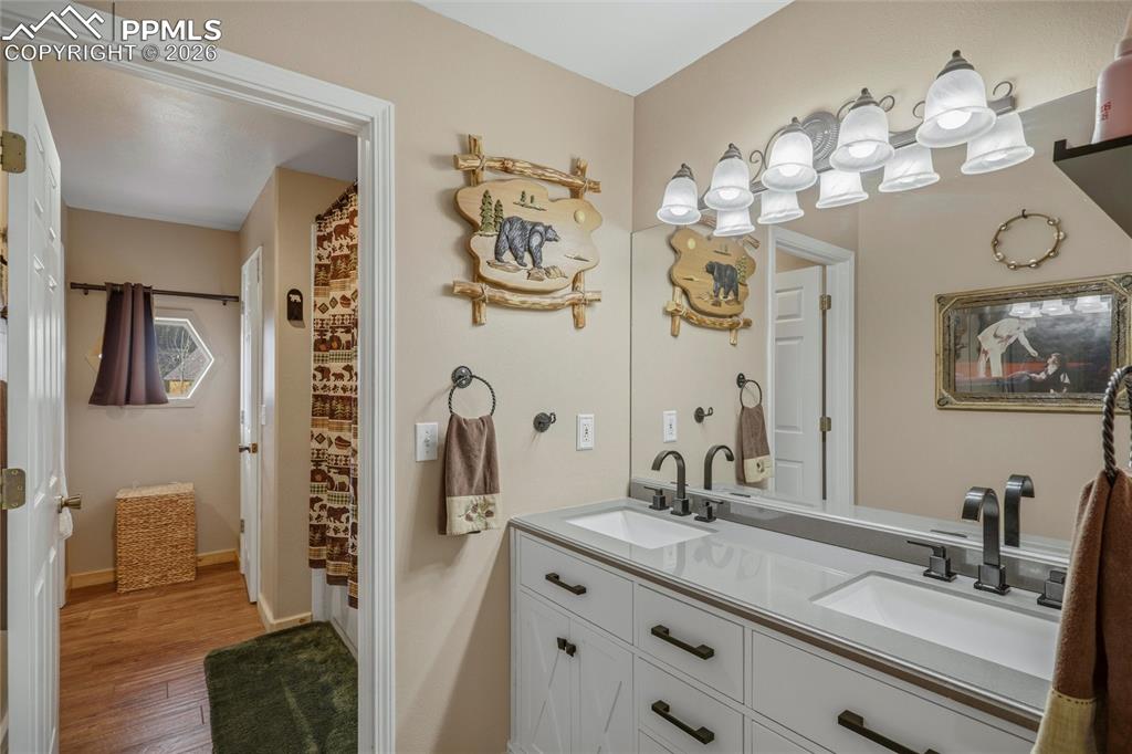 Image 22 of 50: Full bath with double vanity, a shower with curtain, and light wood finishe