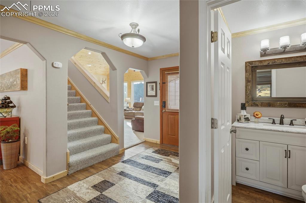Image 23 of 50: Foyer entrance with crown molding, wood finished floors, and arched walkway