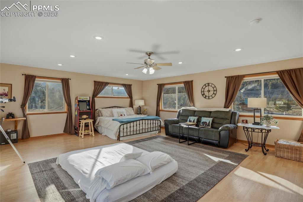 Image 29 of 50: Bedroom with wood finished floors, ceiling fan, and recessed lighting