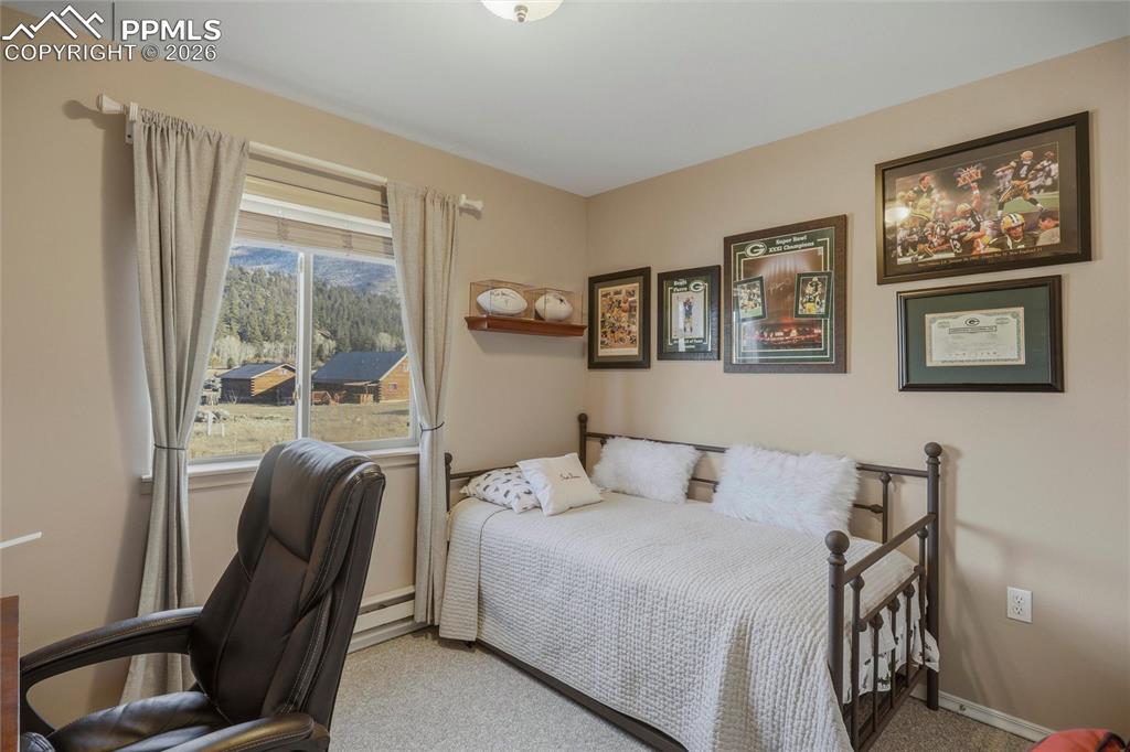 Image 31 of 50: Carpeted bedroom featuring baseboard heating and a desk