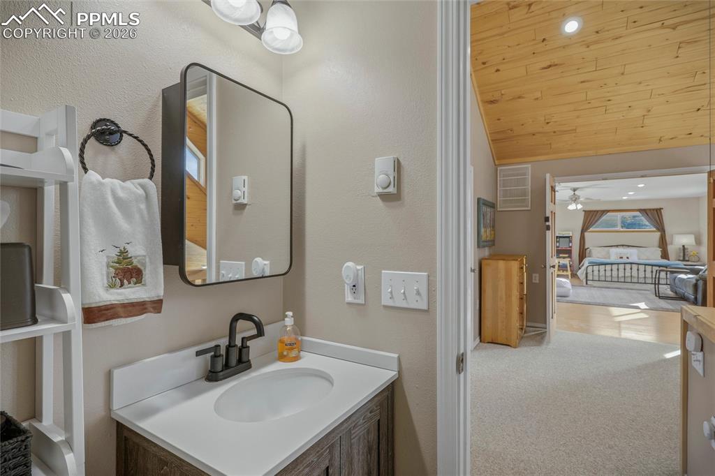 Image 33 of 50: Bathroom with vanity, a vaulted wood ceiling, light carpet, recessed lighti