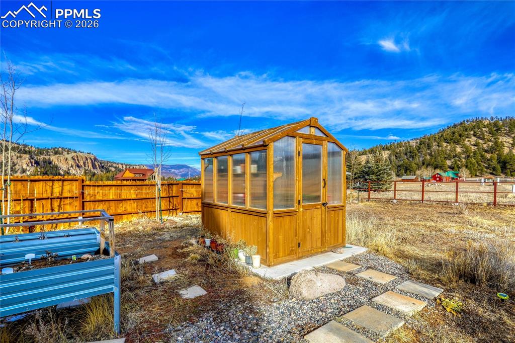 Image 43 of 50: View of greenhouse with a mountain view, a fenced backyard, and a sunroom