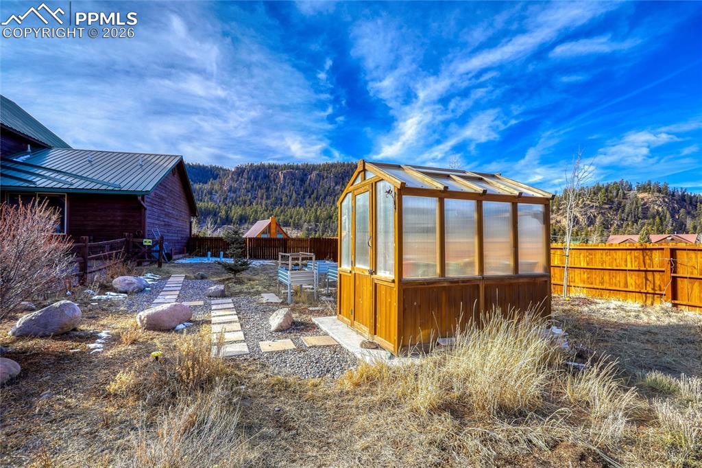 Image 44 of 50: View of greenhouse with a fenced backyard