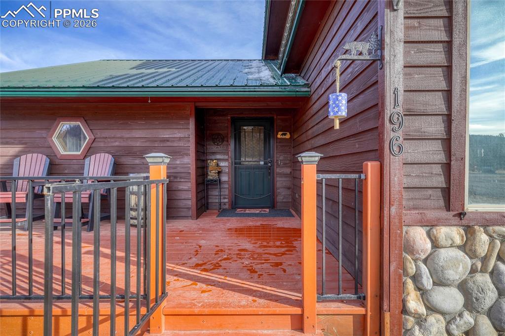 Image 7 of 50: Doorway to property with a wooden deck and a metal roof