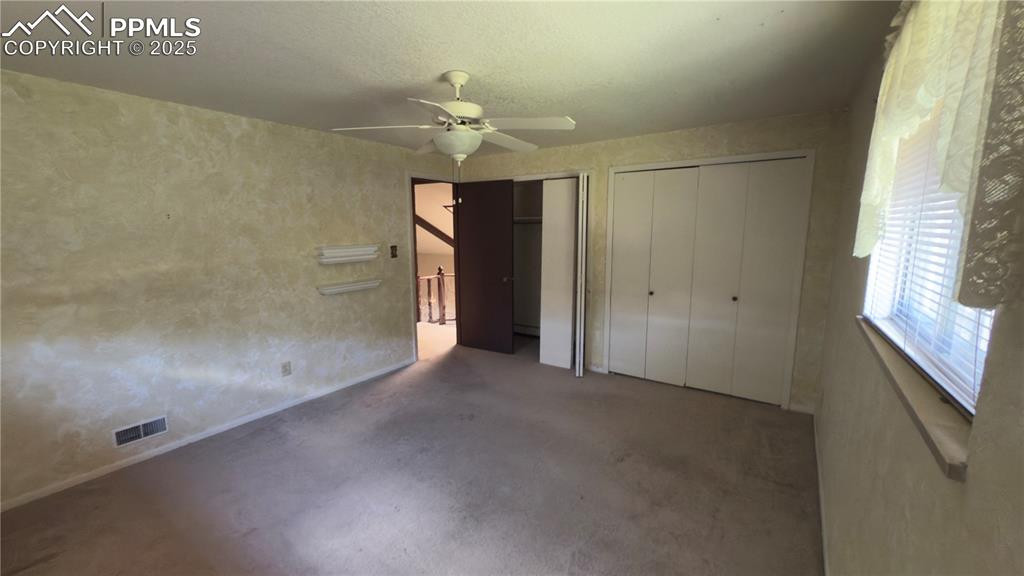 Image 11 of 17: Upper bedroom with two closets, a ceiling fan