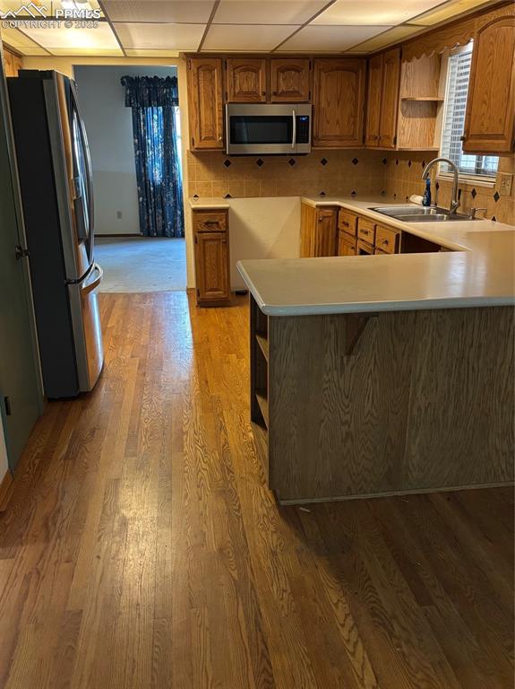 Image 5 of 17: Kitchen featuring open shelves, brown cabinetry, light countertops, stainle