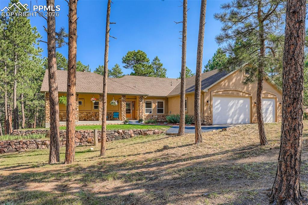 Image 40 of 49: Ranch-style custom built house featuring a shingled roof, stone siding, an 
