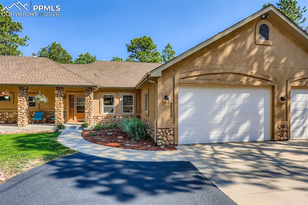 Image 41 of 49: View of front of house with stone siding, driveway, and stucco siding