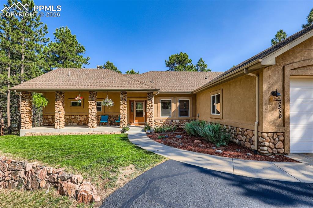 Image 42 of 49: View of front of home featuring stone siding, an attached garage, roof with