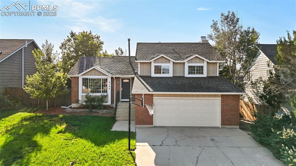 Caption: Tri-level home featuring driveway, brick siding, a chimney, an attached garage, and a shingled roof